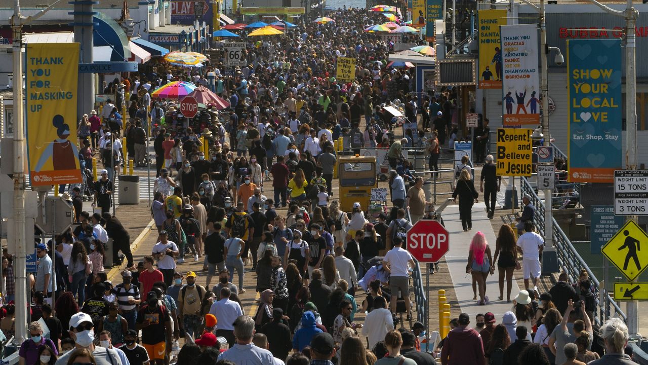People crowd the Santa Monica Pier in Santa Monica, Calif., Saturday, May 29, 2021. (AP Photo/Damian Dovarganes)