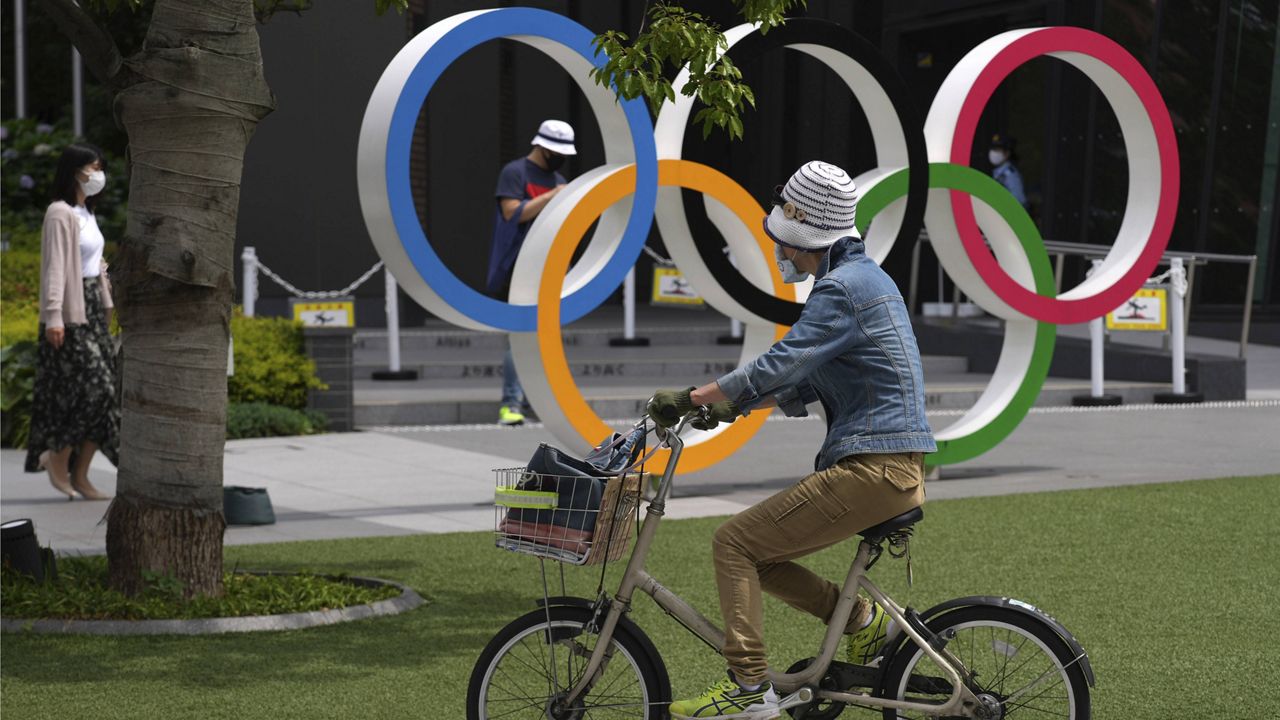 A woman rides a bicycle near the Olympic rings Wednesday in Tokyo. (AP Photo/Eugene Hoshiko)