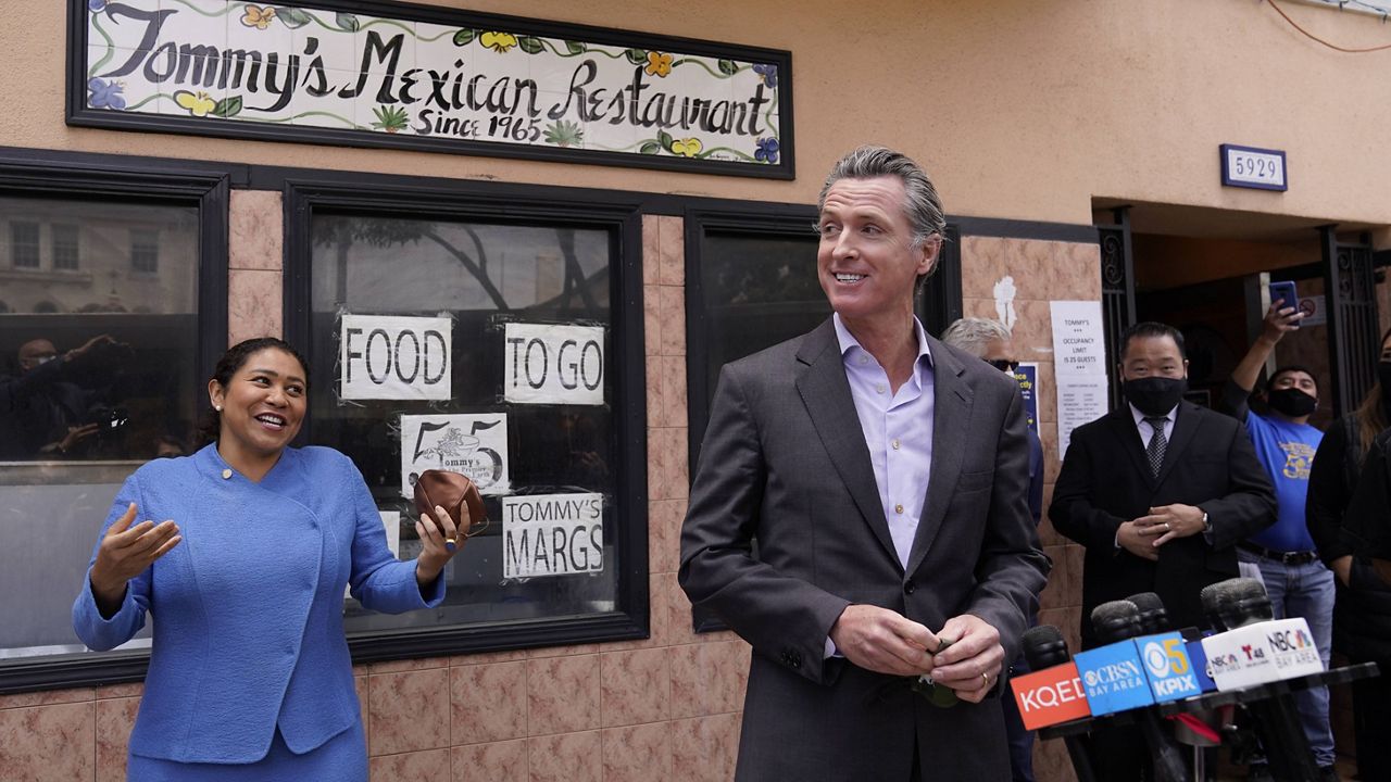 California Gov. Gavin Newsom prepares to speak at a news conference about relief for restaurants as San Francisco Mayor London Breed laughs and looks on outside Tommy's Mexican Restaurant in San Francisco, on Thursday, June 3, 2021. (AP Photo/Eric Risberg)