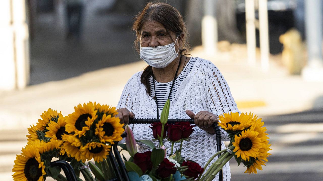Street vendor Dina Barrera, who said she has received the COVID-19 vaccine, wears a face mask while selling flowers in Los Angeles Saturday, Jun. 5, 2021. (AP Photo/Damian Dovarganes)