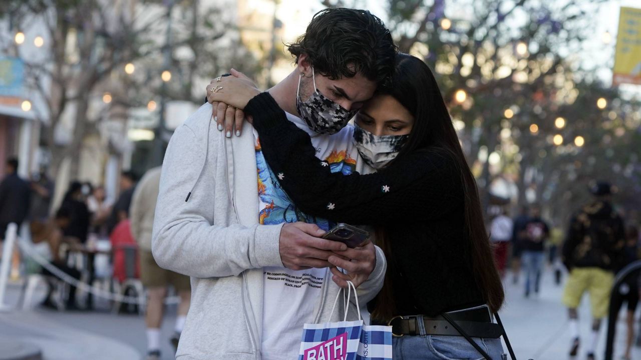 Shoppers embrace and wear masks amid the COVID-19 pandemic on The Promenade, June 9, 2021, in Santa Monica, Calif. (AP Photo/Marcio Jose Sanchez)