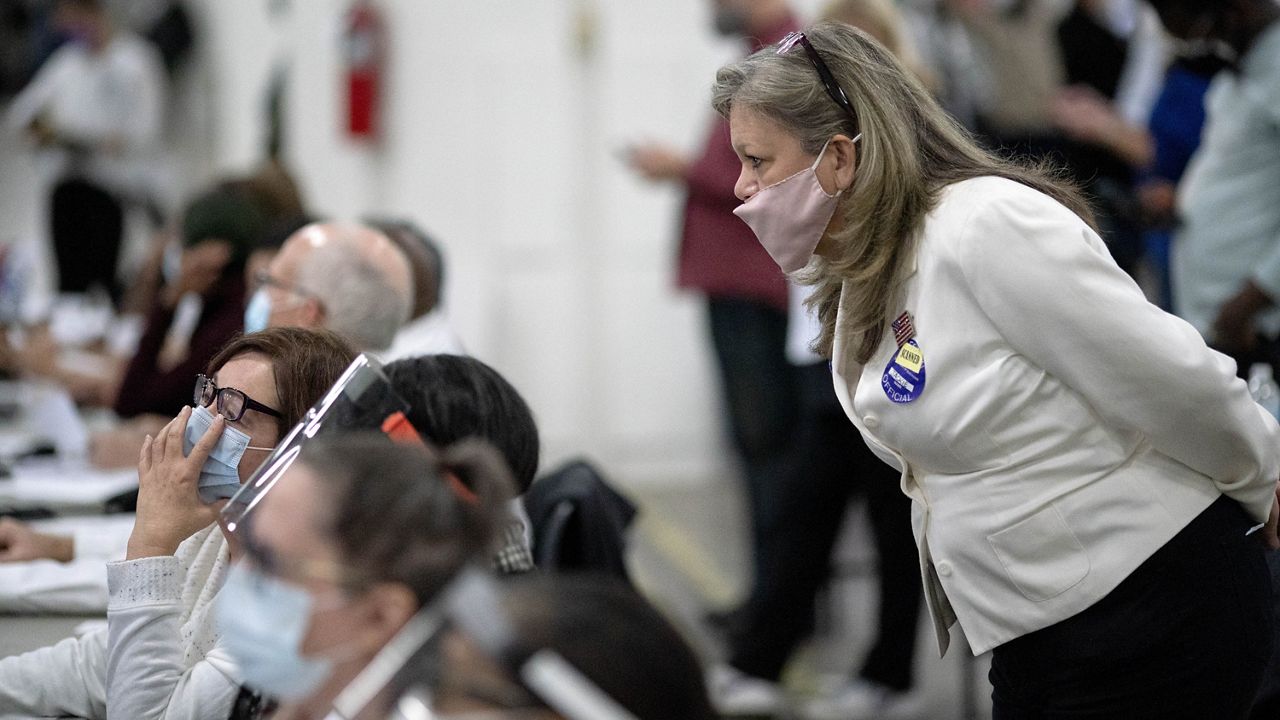 FILE - In this Wednesday, Nov. 4, 2020, file photo, a Republican election challenger at right watches over election inspectors as they examine a ballot as votes are counted into the early morning hours at the central counting board in Detroit. (AP Photo/David Goldman, File)