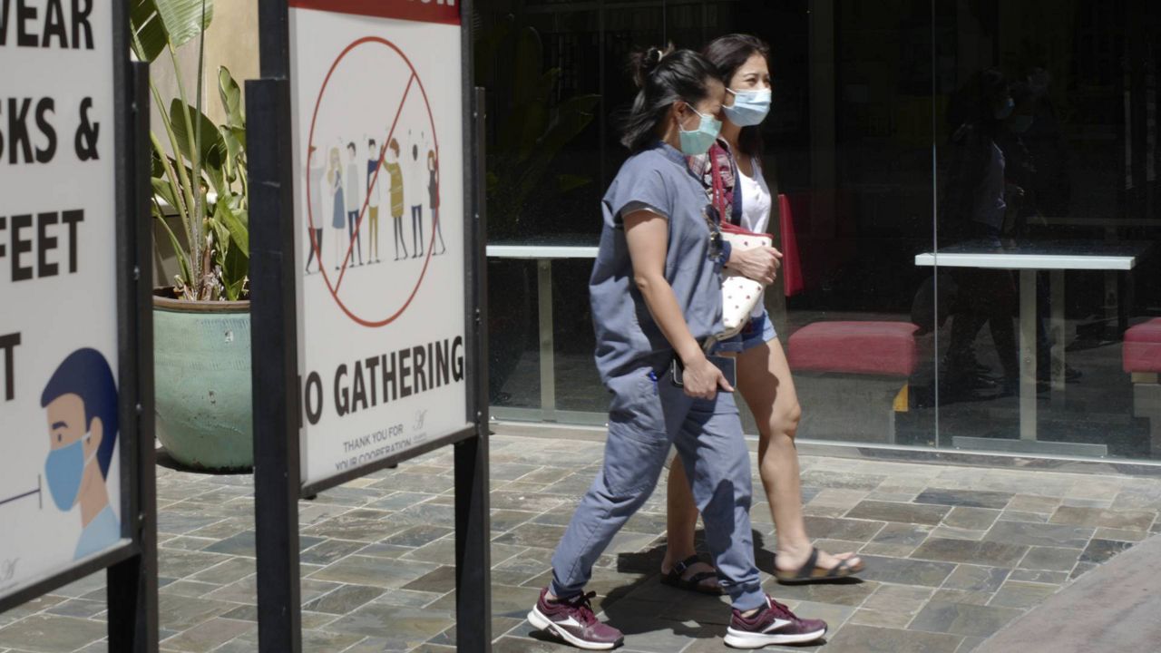 Customers wear face masks in an outdoor mall with closed business amid the COVID-19 pandemic in Los Angeles Friday, June 11, 2021. (AP Photo/Damian Dovarganes)