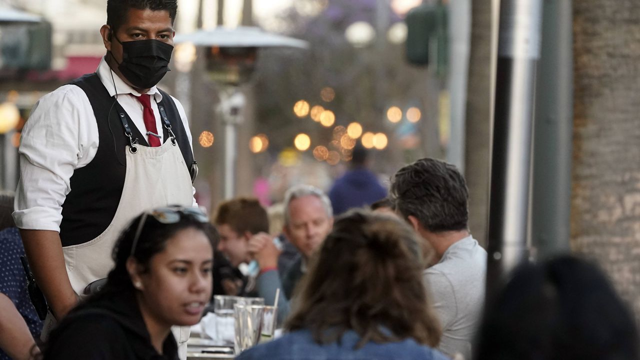 In this June 9, 2021, file photo, a server tends to customers in an outdoor dining area amid the COVID-19 pandemic on The Promenade, in Santa Monica, Calif. (AP Photo/Marcio Jose Sanchez, File)