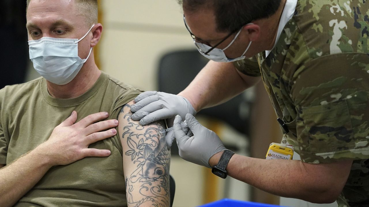 FILE - In this Dec. 16, 2020, file photo, Staff Sgt. Travis Snyder, left, receives the first dose of the Pfizer COVID-19 vaccine given at Madigan Army Medical Center at Joint Base Lewis-McChord in Washington state, south of Seattle. (AP Photo/Ted S. Warren, File)