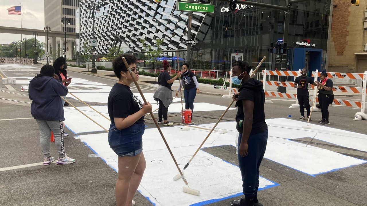 Students from University Prep Art Design celebrate Juneteenth by repainting a street mural, "Power To The People," in downtown Detroit on Saturday, June 19, 2021. (AP Photo/Ed White)