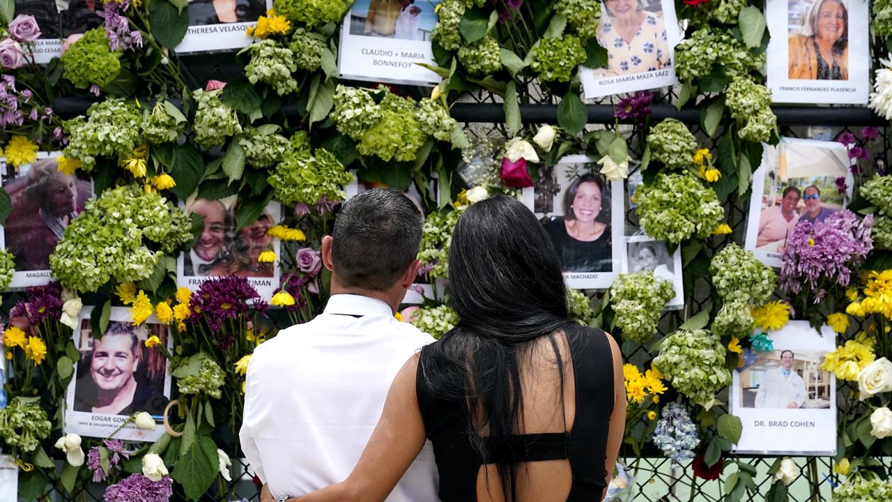 People stand near a make-shift memorial outside St. Joseph Catholic Church near the Champlain Towers South residential condo, Tuesday, June 29, 2021, in Surfside, Fla. (AP Photo/Gerald Herbert)