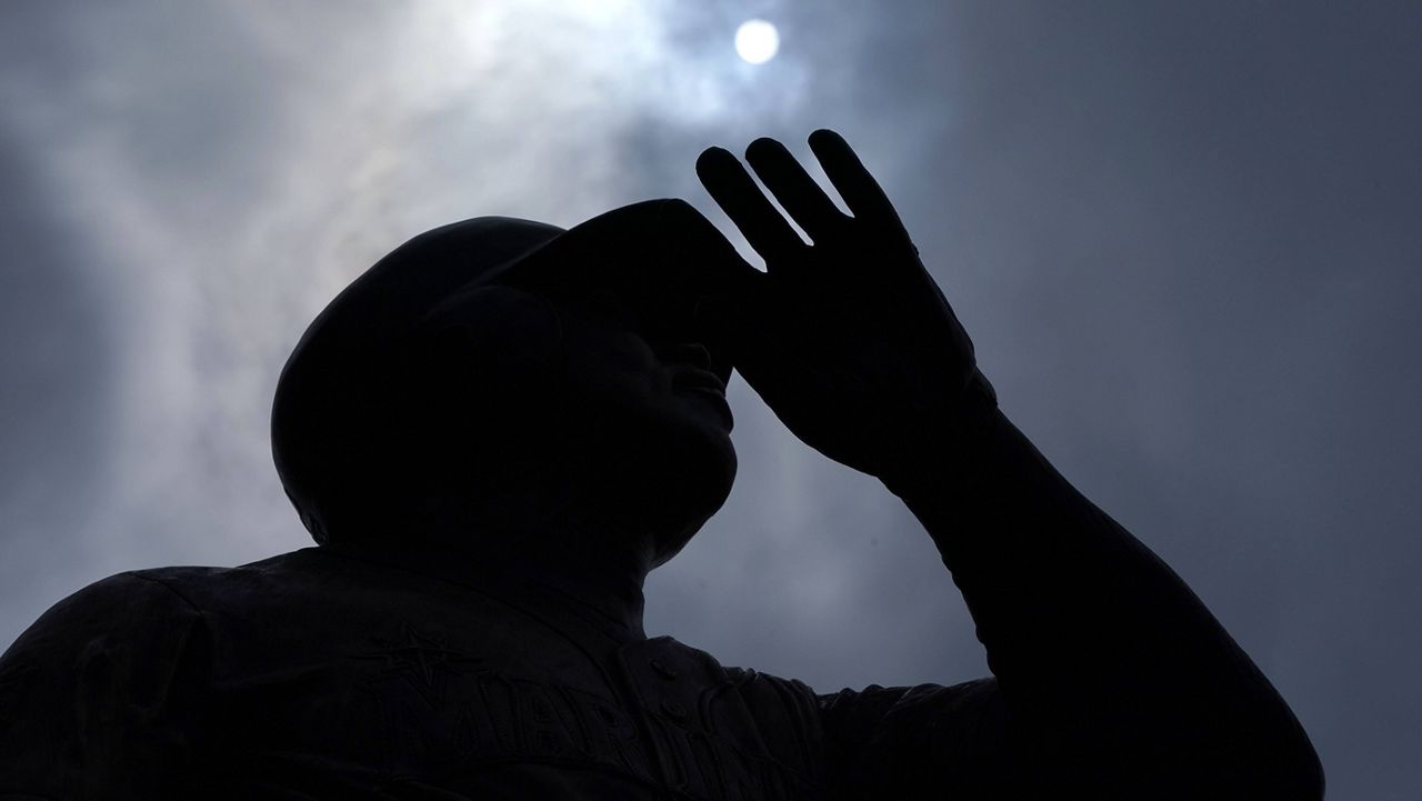 The sun is seen through moving clouds Wednesday above the statue of Seattle Mariners Hall of Famer Ken Griffey Jr. at T-Mobile Park in Seattle. (AP Photo/Ted S. Warren)