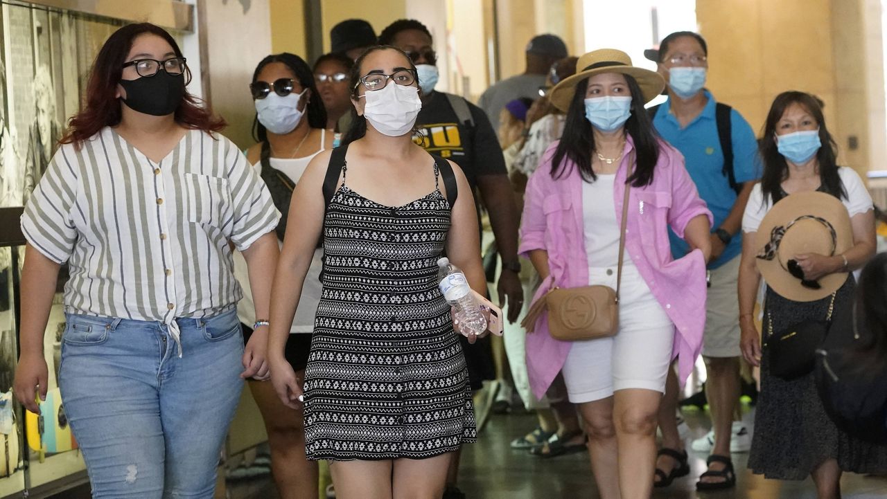 Visitors wear masks as they walk in a shopping district Thursday in the Hollywood section of Los Angeles. (AP Photo/Marcio Jose Sanchez)