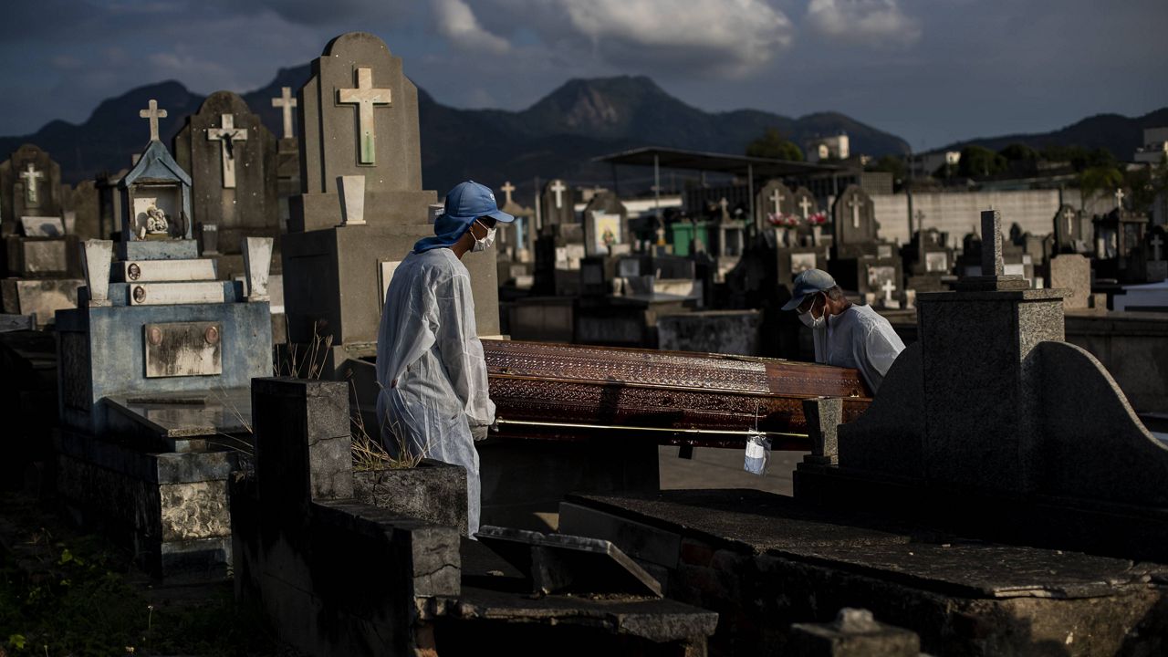 Cemetery workers carry the coffin that contains the remains of 89-year-old Irodina Pinto Ribeiro, who died from COVID-19-related complications, at the Inhauma cemetery in Rio de Janeiro on June 18. (AP Photo/Bruna Prado, File)