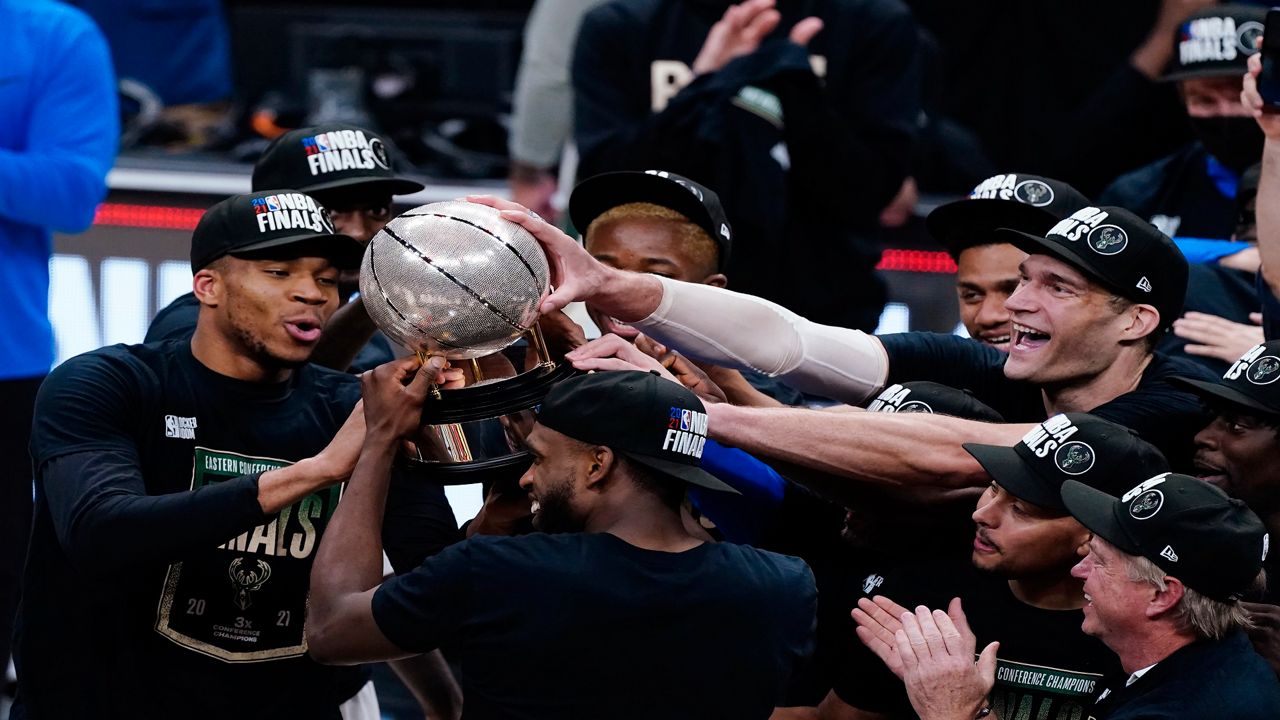 Milwaukee Bucks' Khris Middleton, center, shoots between multiple Atlanta Hawks defenders during the first half of Game 5 of the NBA Eastern Conference Finals Thursday, July 1, 2021, in Milwaukee. (AP Photo/Aaron Gash)