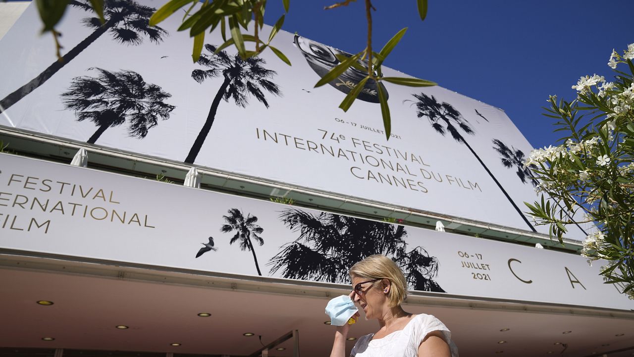 A member of the public walks past the Palais des Festival with a face mask during preparations for the 74th international film festival, Cannes, southern France, July 5, 2021. (AP Photo/ Vadim Ghirda)