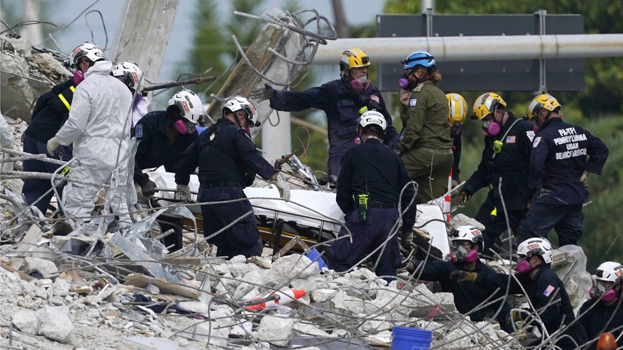 rescue workers move a stretcher containing recovered remains at the site of the collapsed Champlain Towers South condo building Monday. (AP Photo/Lynne Sladky, File)