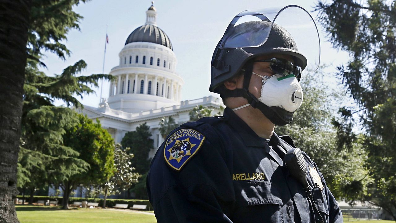 In this May 7, 2020, file photo, California Highway Patrol Officer S. Arellano wears a face mask as he and other officers form a line around at anticipation of a protest rally at the the state Capitol in Sacramento, Calif. (AP Photo/Rich Pedroncelli, File)