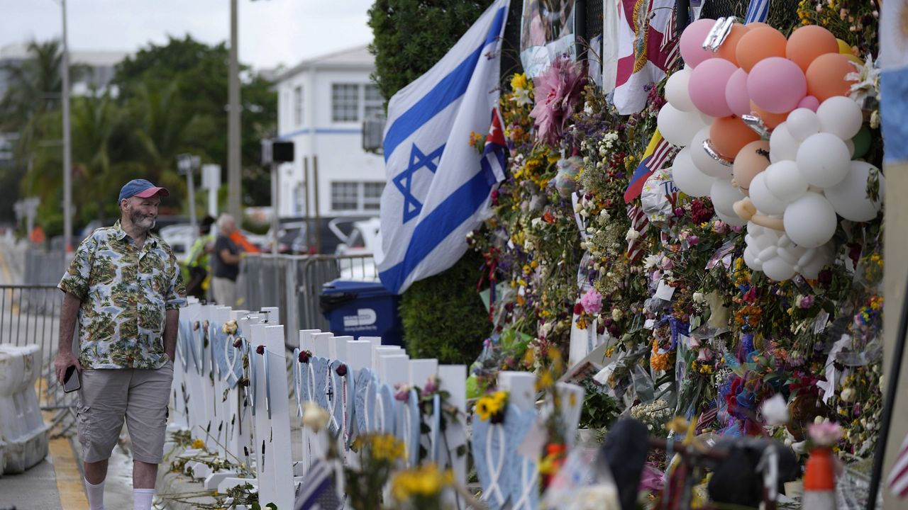 Peter Martin, of New York, pays his respects Monday morning at a makeshift memorial for the victims of the Champlain Towers South building collapse. (AP Photo/Rebecca Blackwell)