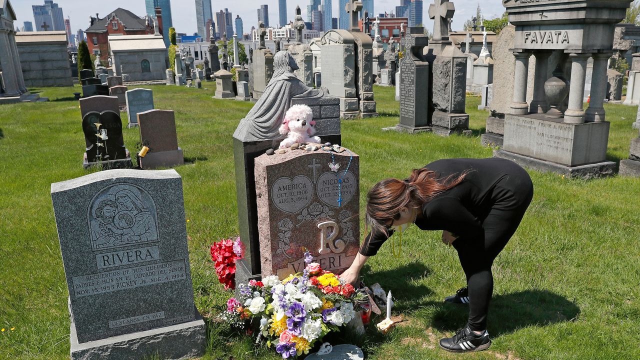 FILE - In this Sunday, May 10, 2020 file photo, Sharon Rivera adjusts flowers and other items left at the grave of her daughter, Victoria, at Calvary Cemetery in New York, on Mother's Day. Victoria died of a drug overdose in Sept. 22, 2019, when she just 21 years old. (AP Photo/Kathy Willens, File)