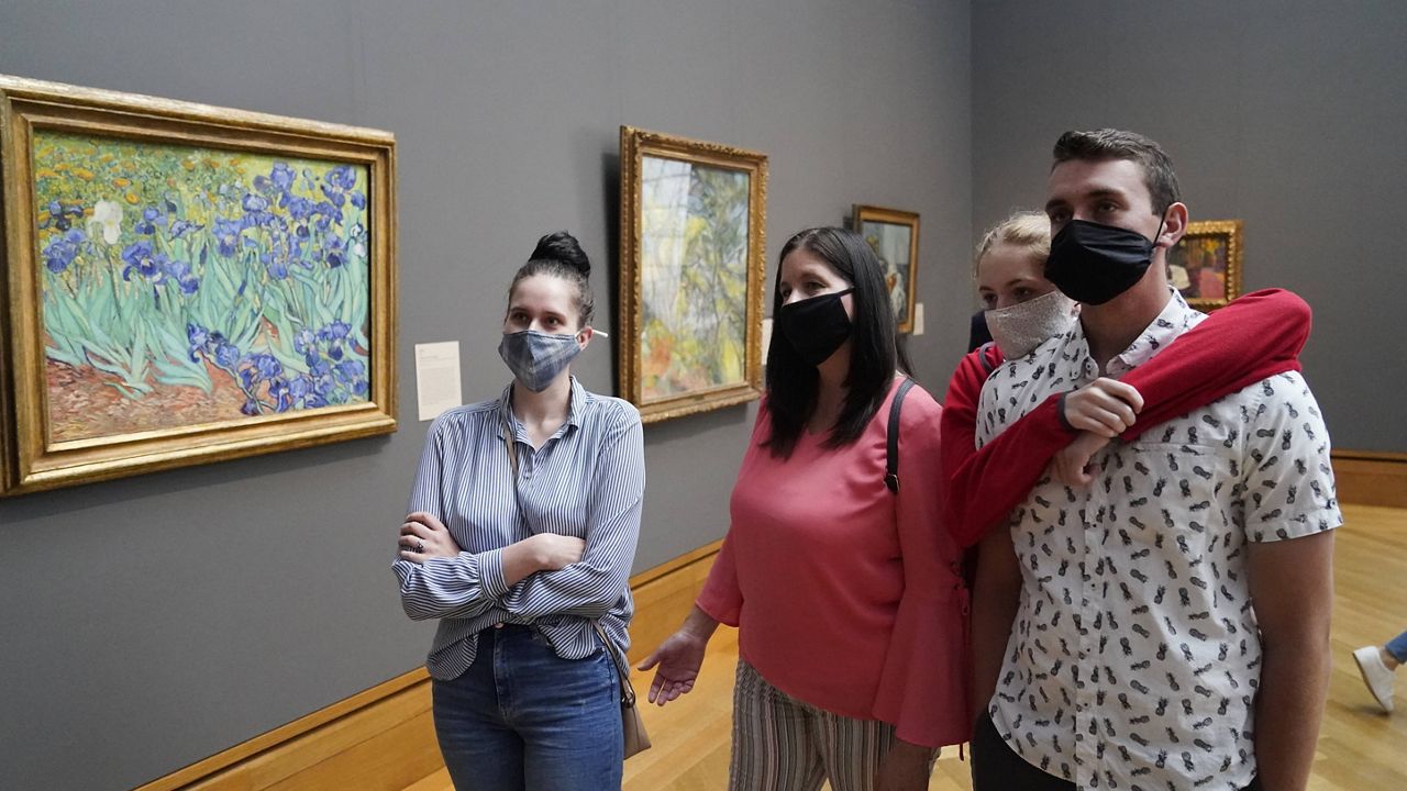 In this Wednesday, May 26, 2021 file photo, visitors wear masks as they view art, including Vincent van Gogh's "Irises", at left, at the newly re-opened Getty Center amid the COVID-19 pandemic in Los Angeles.