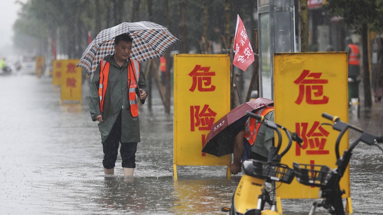 Staff members set up warning signs with the words "Danger!" at a waterlogged area in Wuzhi County in central China's Henan Province on Tuesday.  (Feng Xiaomin/Xinhua via AP)