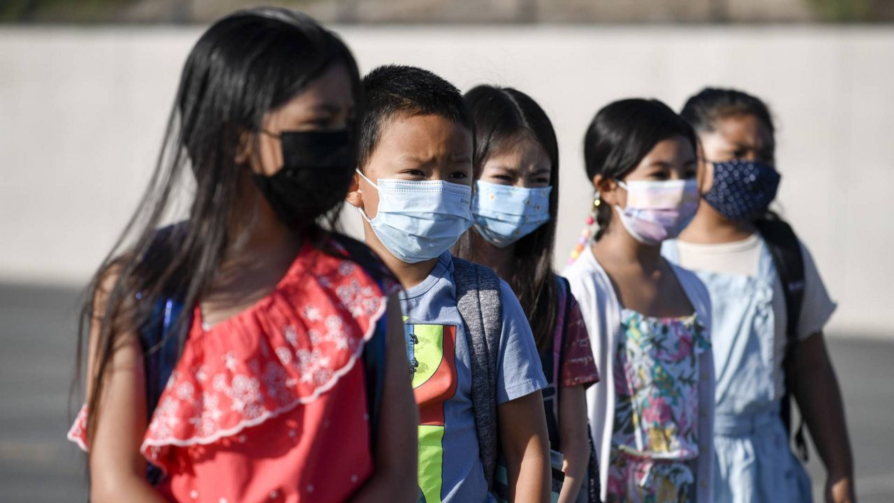 Masked students wait to be taken to their classrooms at Enrique S. Camarena Elementary School, Wednesday, July 21, 2021, in Chula Vista, Calif. (AP Photo/Denis Poroy)