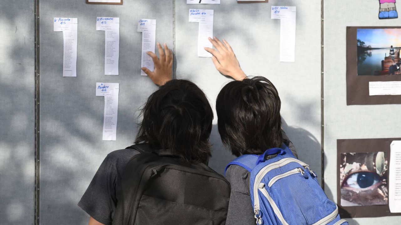 Parents and students look at the class list on the first day of school at Enrique S. Camarena Elementary School, July 21, 2021, in Chula Vista, Calif. (AP Photo/Denis Poroy)