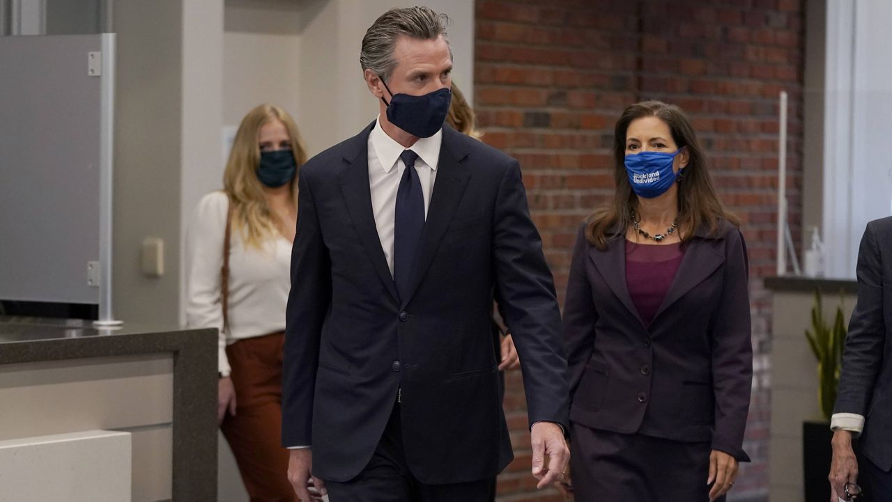 Gov. Gavin Newsom, middle, walks with Oakland Mayor Libby Schaaf at a news conference in Oakland, Calif., Monday, July 26, 2021. (AP Photo/Jeff Chiu)
