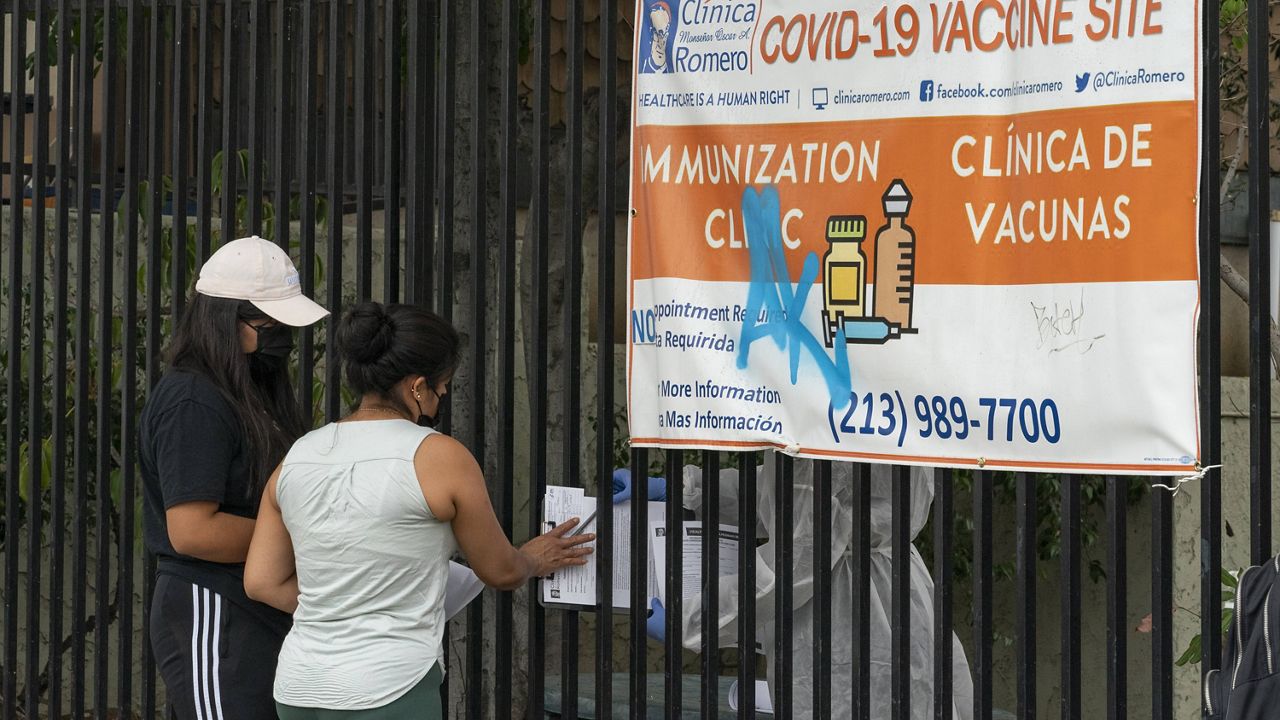 Immigrants fill out forms before getting vaccinated at the Clínica Monseñor Oscar A. Romero in the Pico-Union district of Los Angeles, Monday, July 26, 2021. (AP Photo/Damian Dovarganes)