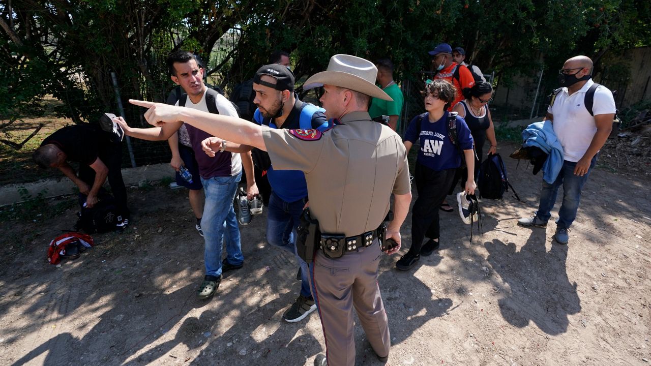In this Wednesday, June 16, 2021 file photo, A Texas Department of Public Safety officer in Del Rio, Texas directs a group of migrants who crossed the border and turned themselves in. (AP Photo)