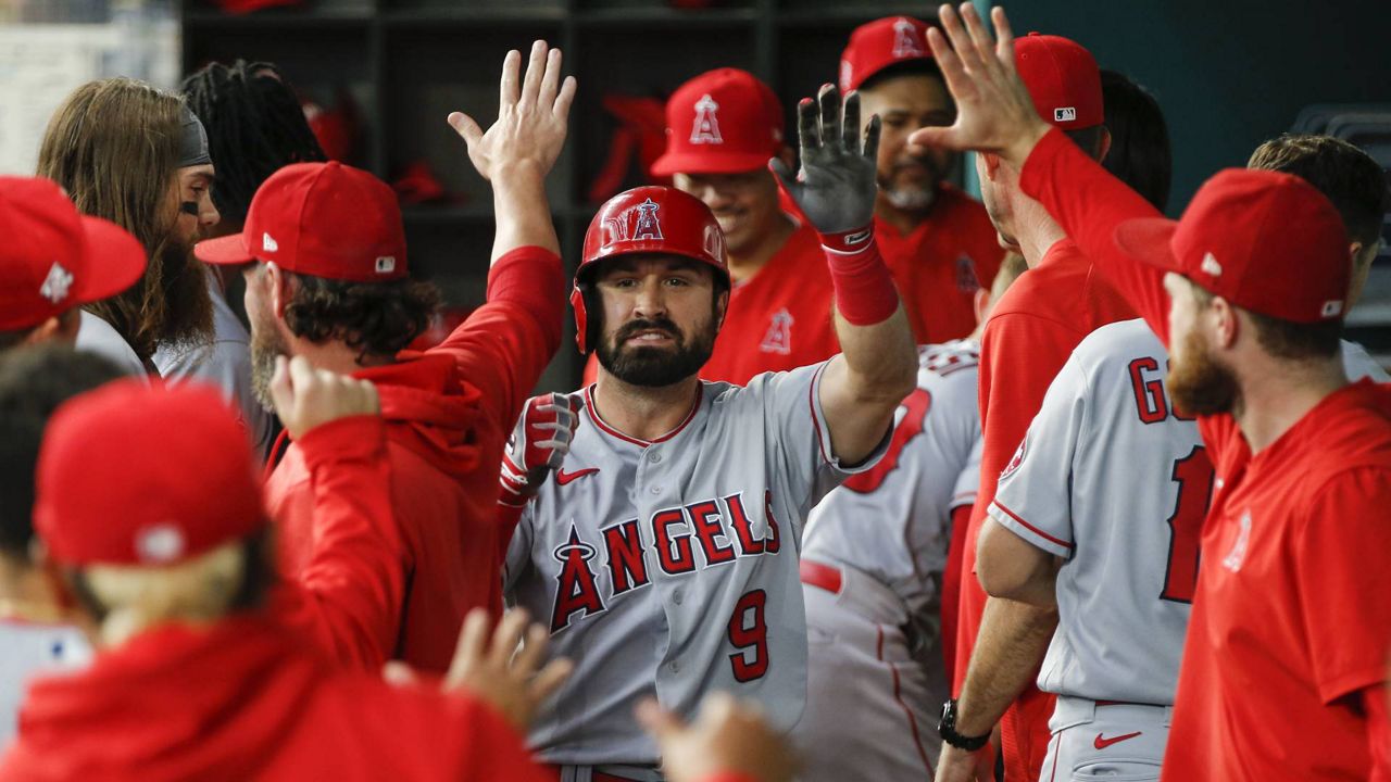 Los Angeles Angels' Adam Eaton (9) is congratulated in the dugout by teammates after hitting a solo home run during the third inning of a baseball game, Aug. 5, 2021, in Arlington, Texas. (AP Photo/Brandon Wade)