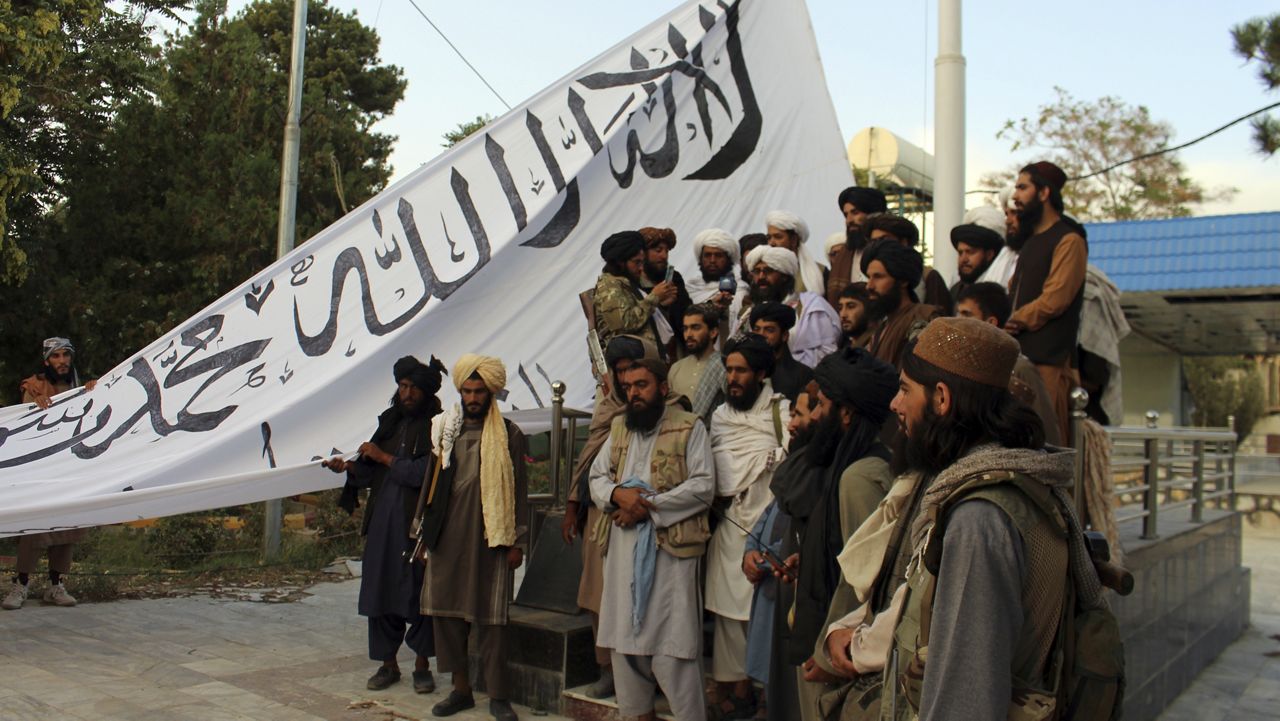 Taliban fighters pose for a photograph while raising their flag at the Ghazni provincial governor's house, in Ghazni, southeastern, Afghanistan, Sunday, Aug. 15, 2021. (AP Photo/Gulabuddin Amiri)