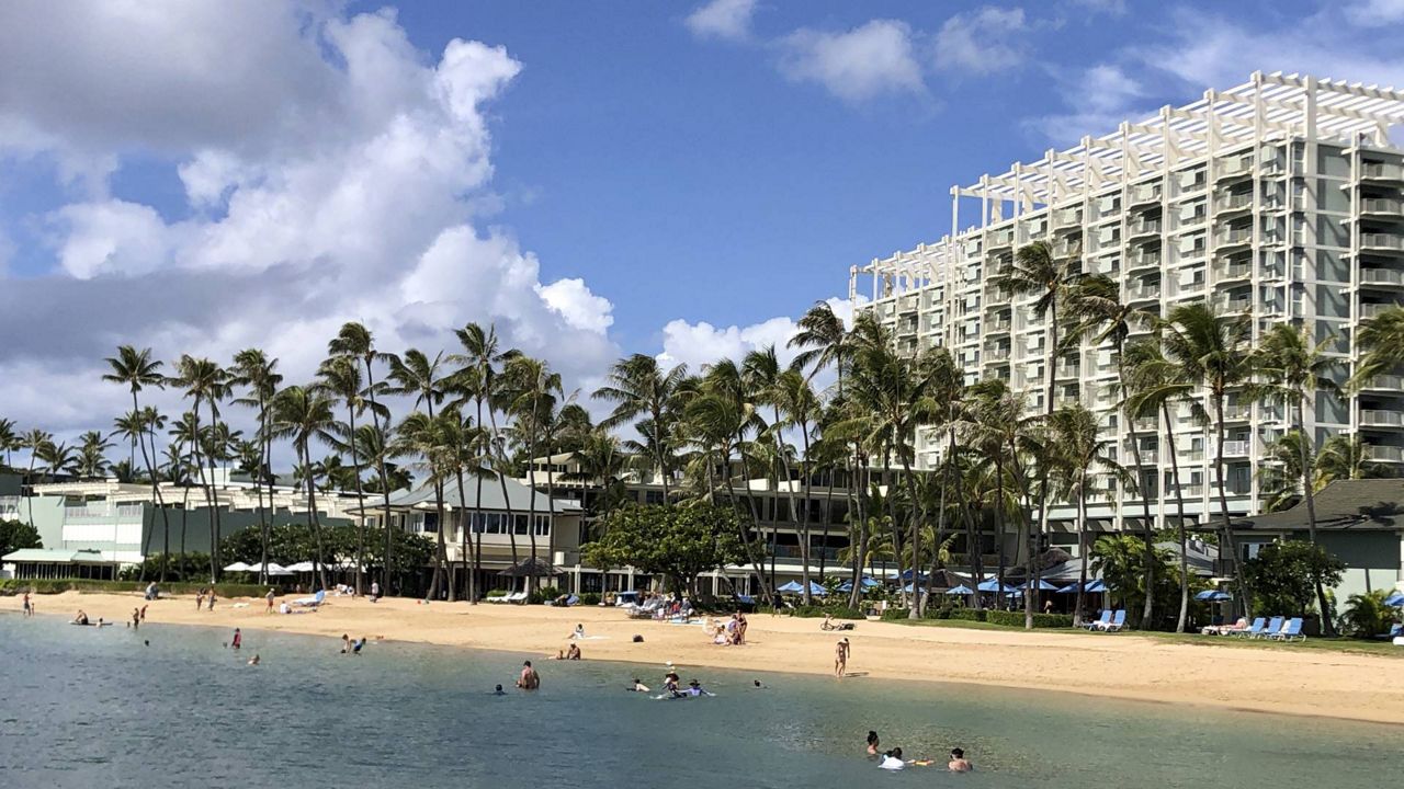 In this Nov. 15, 2020, file photo, people are seen on the beach and in the water in front of the Kahala Hotel & Resort in Honolulu. (AP Photo/Jennifer Sinco Kelleher)