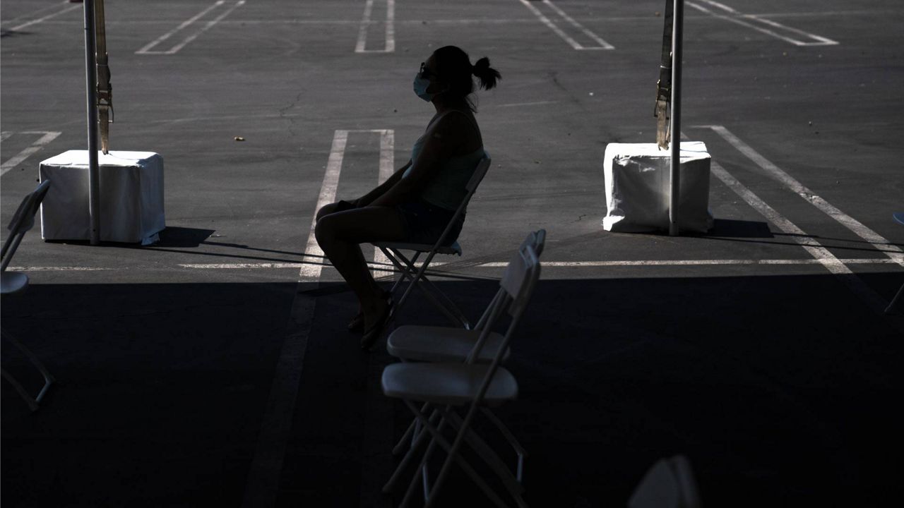 A woman waits in the holding area after receiving the COVID-19 vaccine at a clinic set up in the parking lot of CalOptima Saturday, Aug. 28, 2021, in Orange, Calif. (AP Photo/Jae C. Hong)