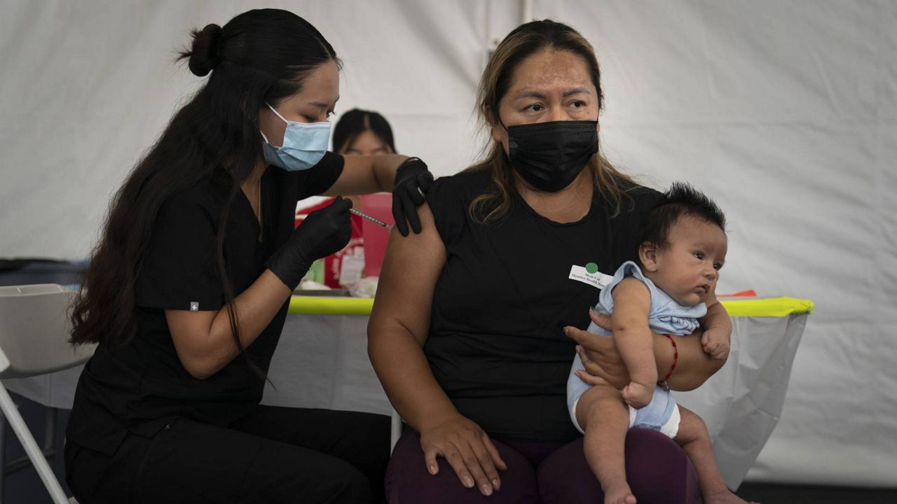 Laura Sanchez, right, holds her 2-month-old son while receiving the Pfizer COVID-19 vaccine from registered nurse Noleen Nobleza at a vaccine clinic on Saturday, Aug. 28, 2021, in Orange, Calif. (AP Photo/Jae C. Hong)