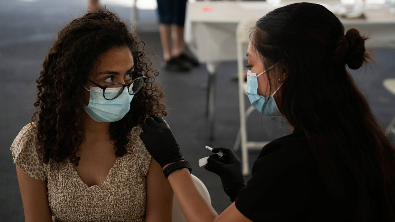 Priscilla Farag, 17, looks at registered nurse, Noleen Nobleza while getting the Pfizer COVID-19 vaccine at a vaccine clinic set up in the parking lot of CalOptima, Aug. 28, 2021, in Orange, Calif. (AP Photo/Jae C. Hong)