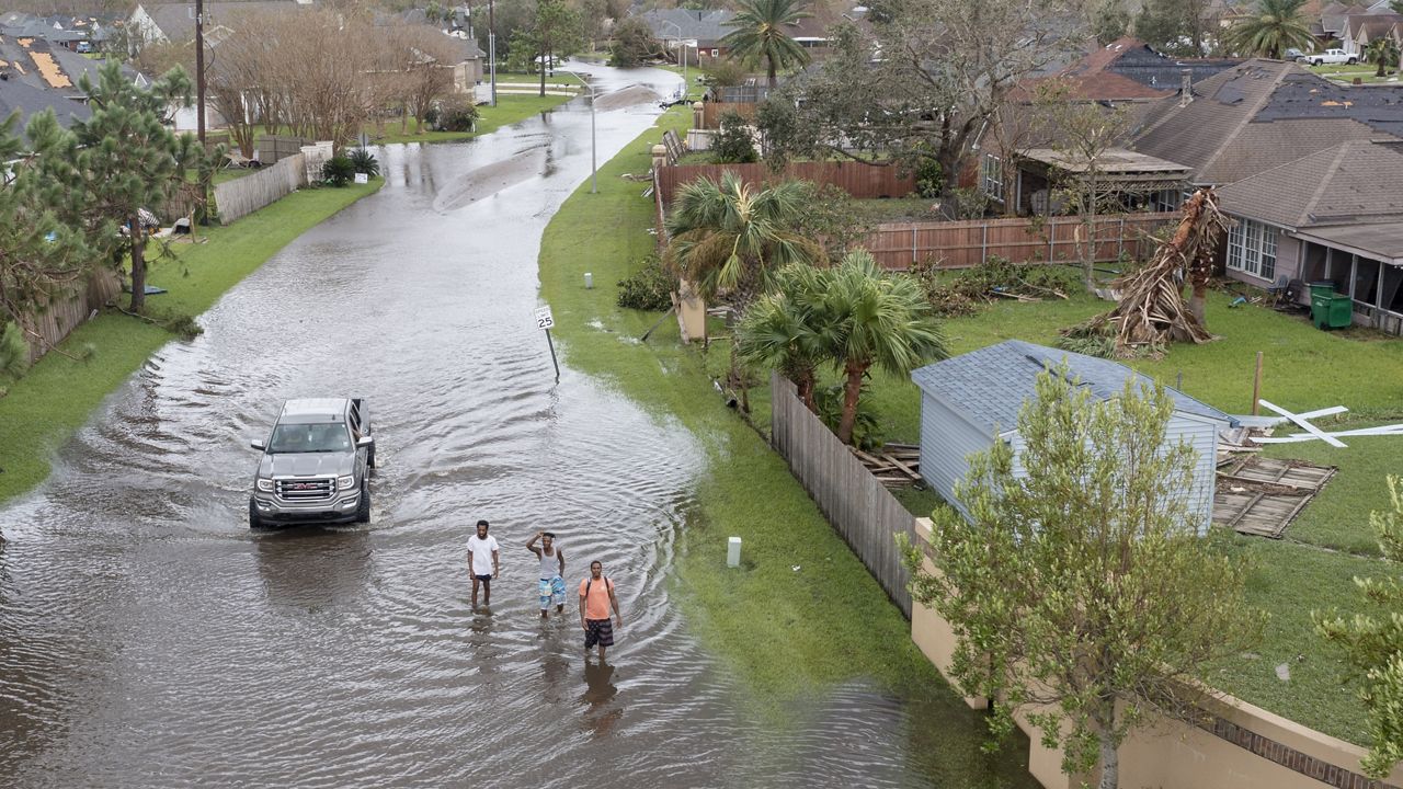 Flooded streets are shown in the Spring Meadow subdivision in LaPlace, La., after Hurricane Ida moved through Monday, Aug. 30, 2021. The individuals in this photo are not related to the alligator attack. (AP Photo/Steve Helber)