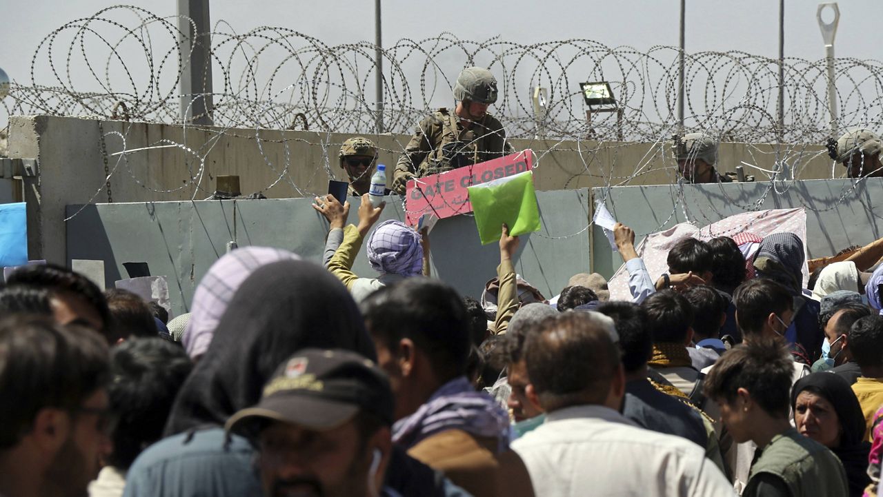 In this Aug. 26 file photo, a U.S. soldier holds a sign indicating a gate is closed as hundreds of people gather near an evacuation control checkpoint on the perimeter of the Hamid Karzai International Airport in Kabul, Afghanistan. (AP Photo/Wali Sabawoon, File)