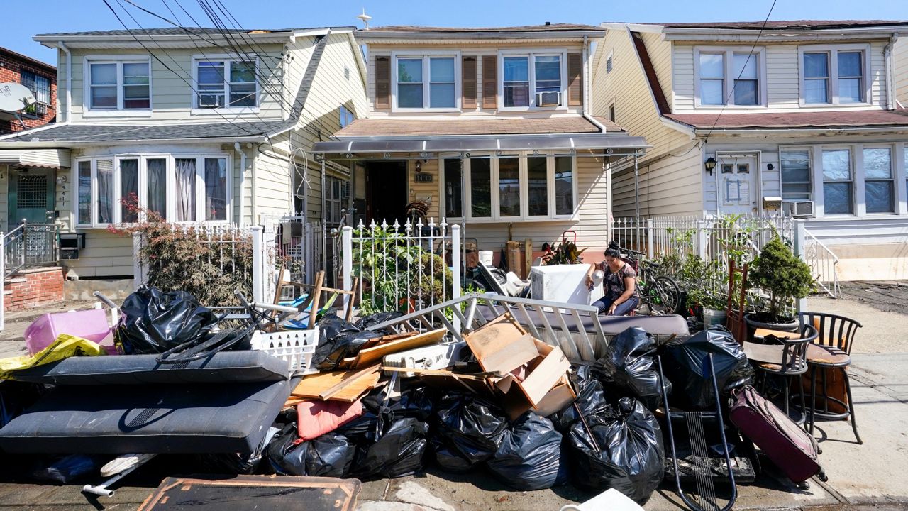 A resident of 153rd St. in Flushing, Queens, sits outside her home with her water logged belongings, Thursday, Sept. 2, 2021. (AP Photo/Mary Altaffer)