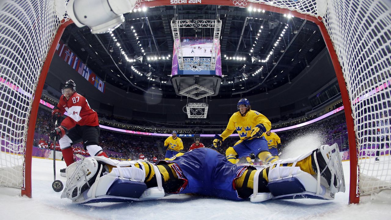 In this Feb. 23, 2014, file photo, Canada forward Sidney Crosby, left, scores a goal past Sweden goaltender Henrik Lundqvist during Winter Olympics in Sochi, Russia. (AP Photo/Julio Cortez, Pool, FIle)