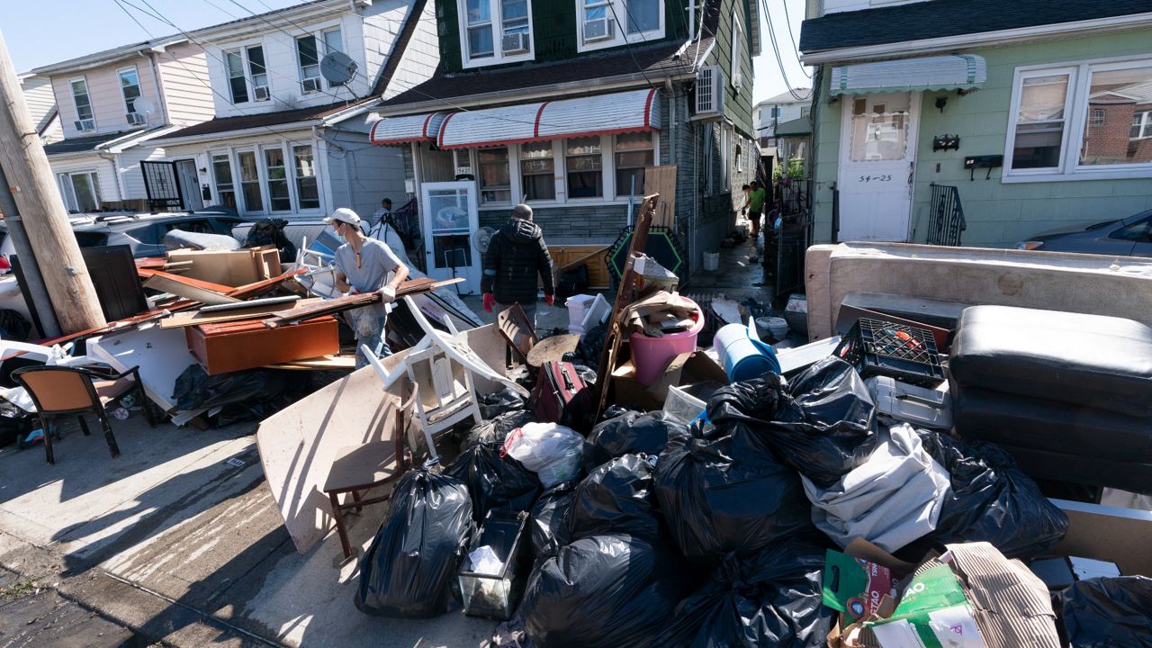 People clear debris and damaged belongings from their homes in Queens, Friday, Sept. 3, 2021. (AP Photo/Mark Lennihan)