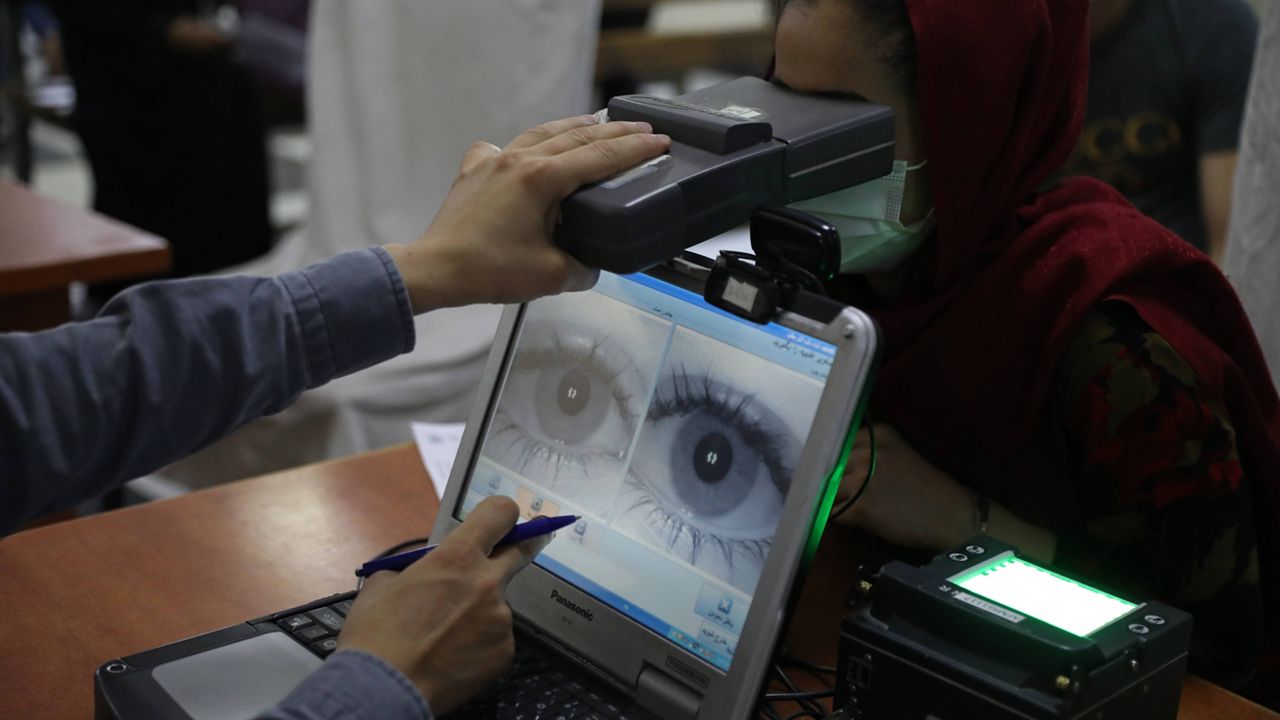 In this June 30, 2021, file photo an employee scans the eyes of a woman for biometric data needed to apply for a passport, at the passport office in Kabul, Afghanistan. (AP Photo/Rahmat Gul, File)
