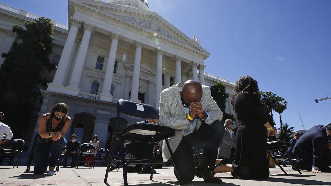 In this June 9, 2020, file photo, Assemblyman Mike Gipson, D-Carson, bows his head as he and other members of the California Legislature kneel to honor George Floyd at the Capitol in Sacramento, Calif. (AP Photo/Rich Pedroncelli, File)