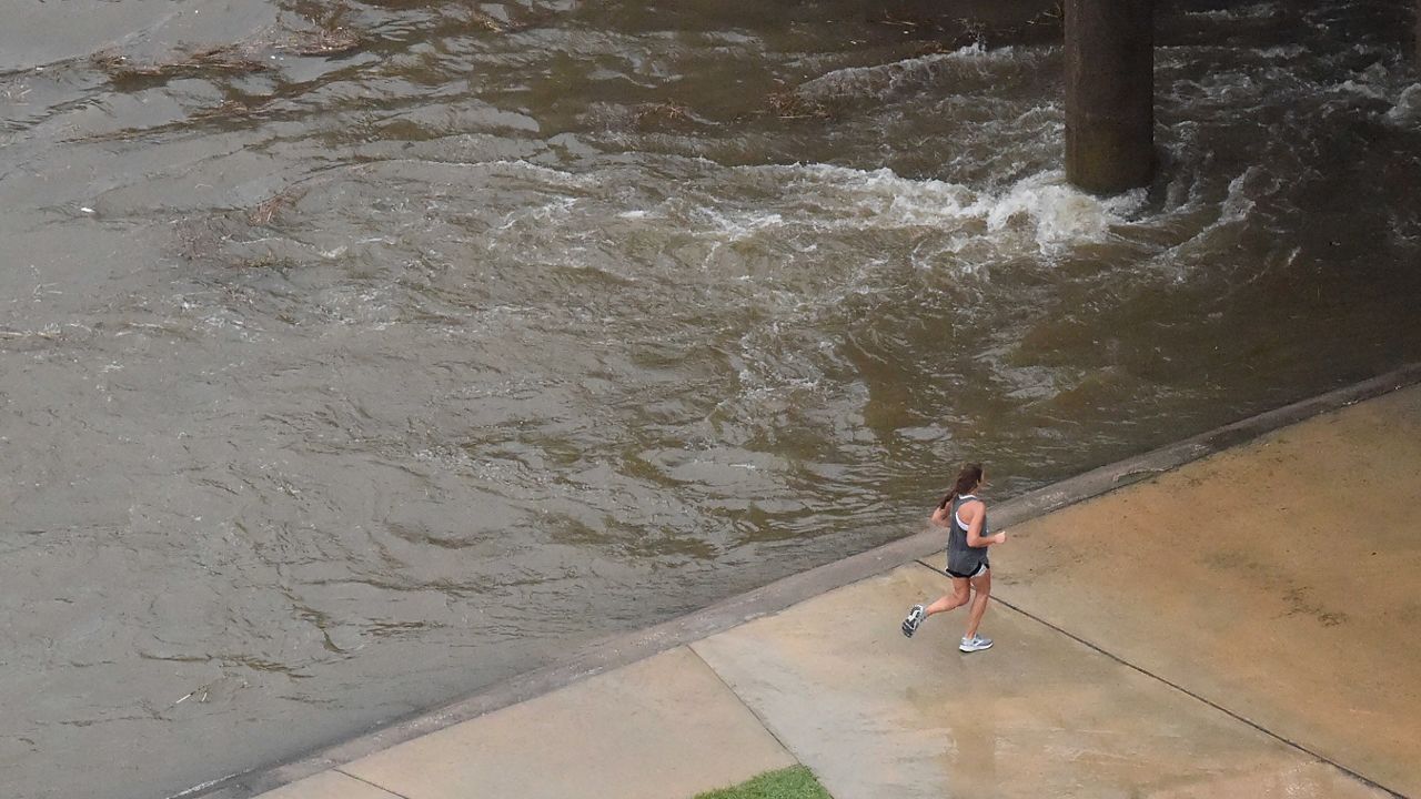 A morning after the storm made landfall as a hurricane, a woman jogs along Brays Bayou, swollen by rainfall from Tropical Storm Nicholas, which knocked out power to a half-million homes and businesses and dumped more than a foot of rain along the same area swamped by Hurricane Harvey in 2017, on Tuesday, Sept. 14, 2021, in Houston, Texas. (AP Photo/Meg Kinnard)