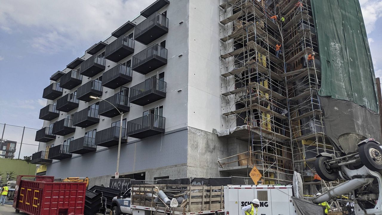 In this June 18, 2021, photo, construction workers finish the exterior of an apartment building downtown Los Angeles. (AP Photo/Damian Dovarganes)