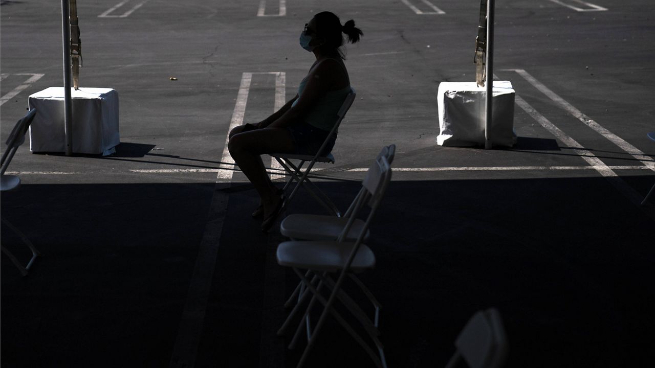 In this Aug. 28, 2021, file photo, a woman waits in the holding area after receiving the COVID-19 vaccine at a clinic set up in the parking lot of CalOptima in Orange, Calif. (AP Photo/Jae C. Hong, File)