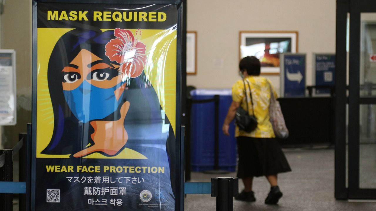 In this Oct. 2, 2020, file photo, a woman walks into the international airport in Honolulu. (AP Photo/Caleb Jones)