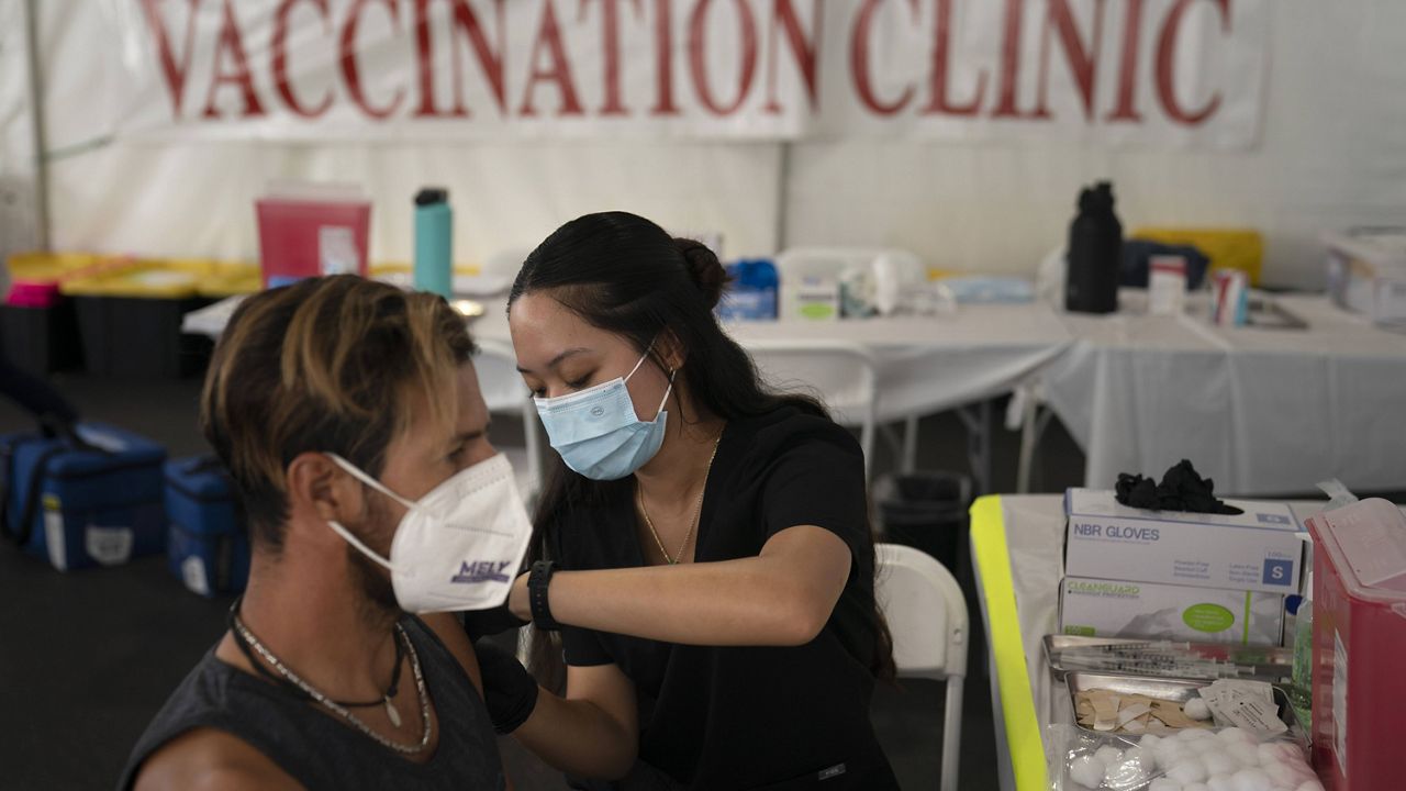 In this Aug. 28, 2021, file photo, registered nurse, Noleen Nobleza, center, inoculates Julio Quinones with a COVID-19 vaccine at a clinic set up in the parking lot of CalOptima in Orange, Calif. (AP Photo/Jae C. Hong, File)
