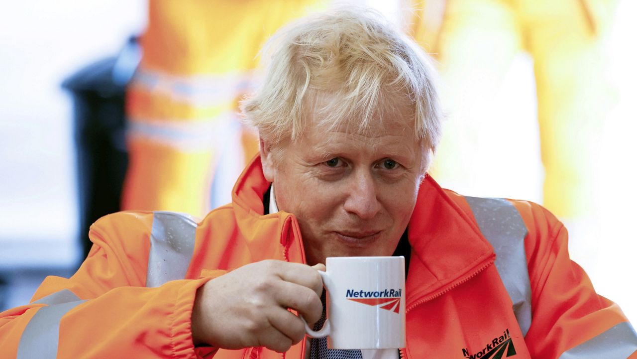 Britain's Prime Minister Boris Johnson holds a mug, during a visit to a construction site in Manchester, England, Monday, Oct. 4, 2021. (Phil Noble/PA via AP)