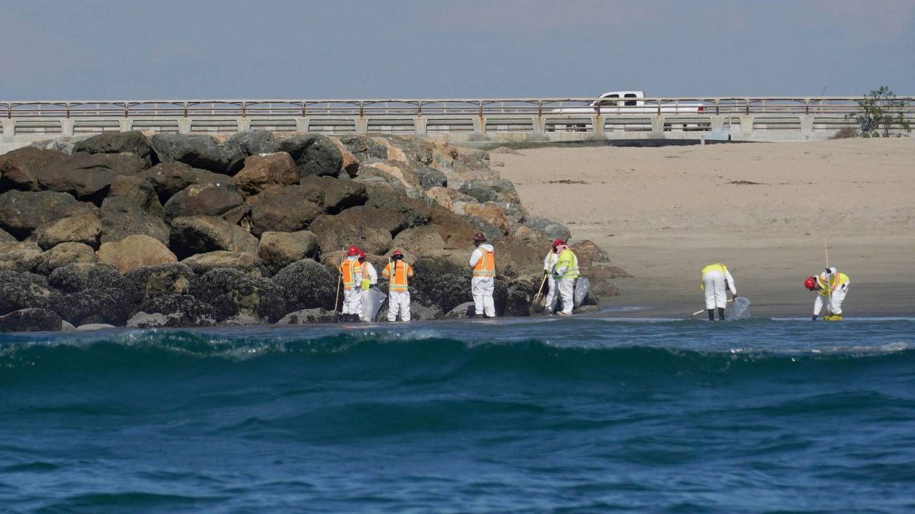 Cleanup crews walking along the beach inspect beach areas and retrieve oil spill debris deposited in Huntington Beach, Calif., Tuesday, Oct. 5, 2021. (AP Photo/Eugene Garcia)
