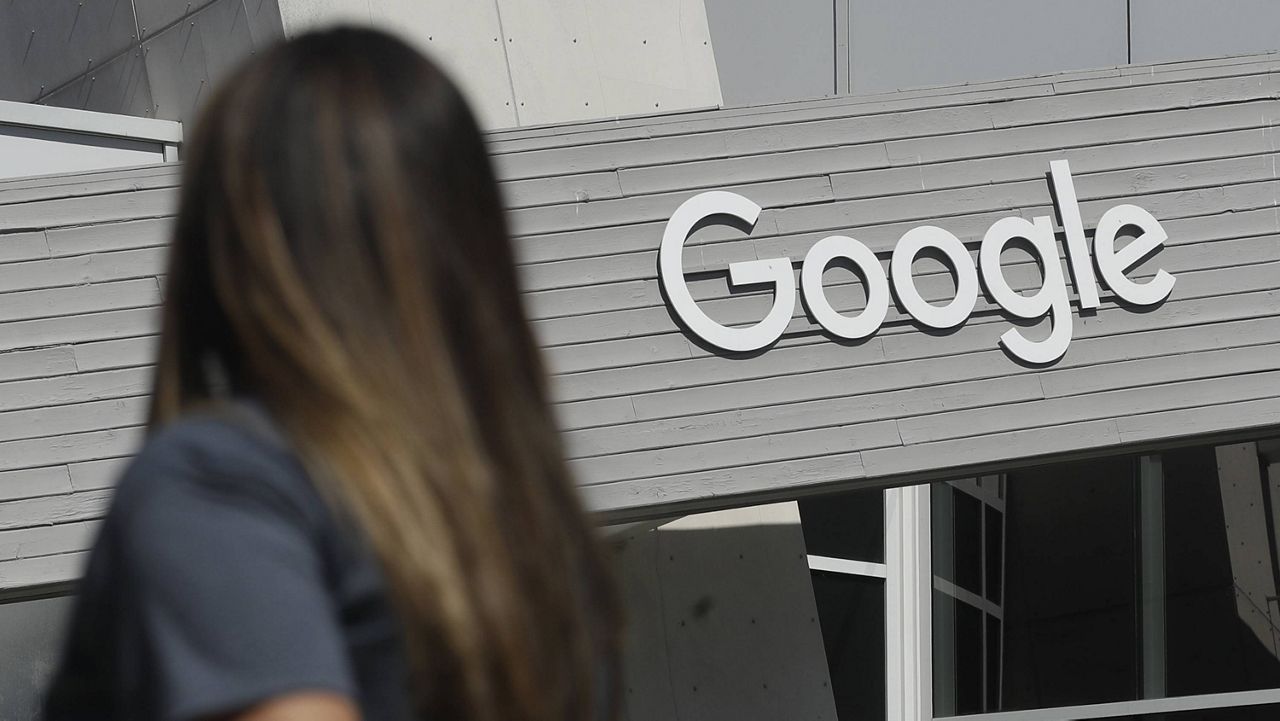 A woman walks below a Google sign on the campus in Mountain View, Calif. (AP Photo/Jeff Chiu, File)