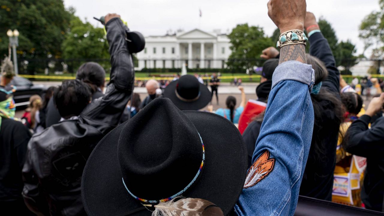 Wolf Ramerez of Houston, Texas, center, joins others with the Carrizo Comecrudo Tribe of Texas in holding up his fists as indigenous and environmental activists protest in front of the White House Monday, Oct. 11, 2021. (AP Photo/Andrew Harnik)