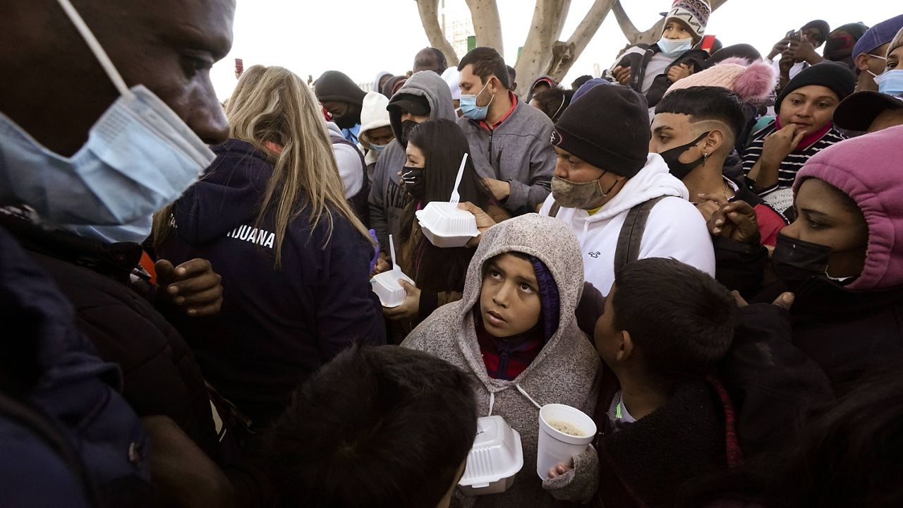 In this Feb. 19 file photo, asylum seekers in Tijuana, Mexico, receive food as they wait for news of policy changes at the border. (AP Photo/Gregory Bull, File)